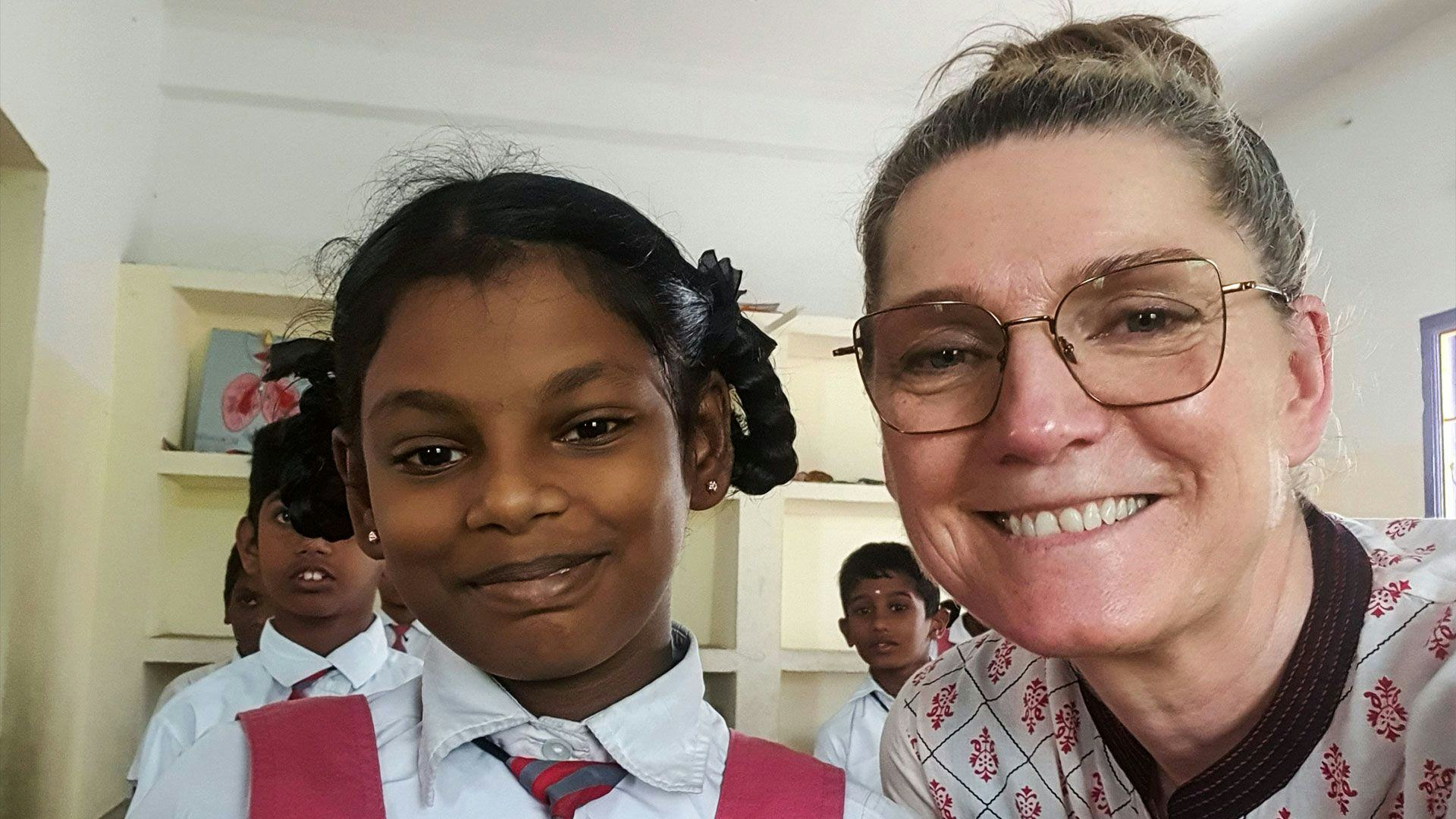 A smiling woman posing with a young girl in school uniform 