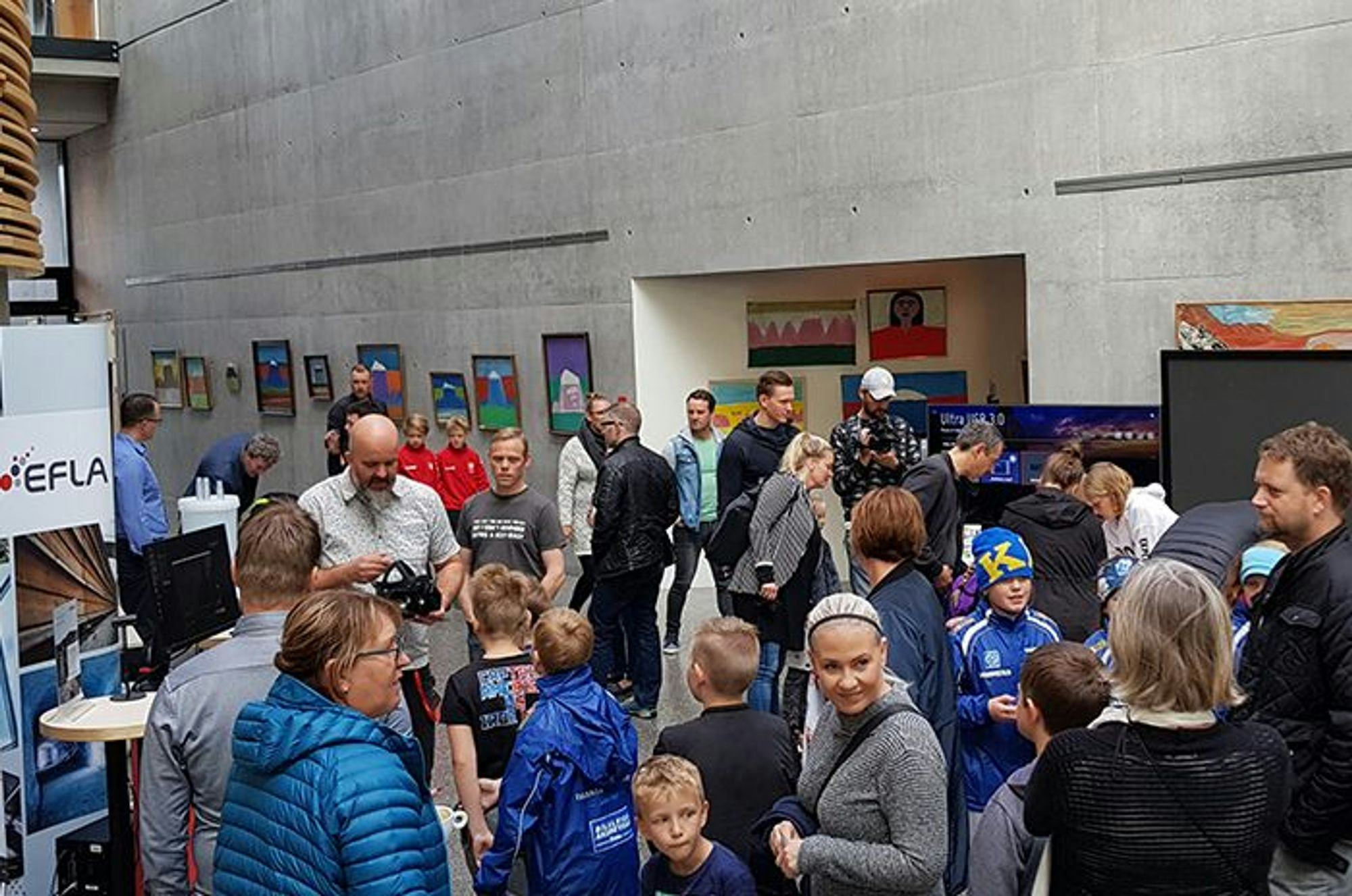 A crowded indoor event with people gathered around an exhibition stand