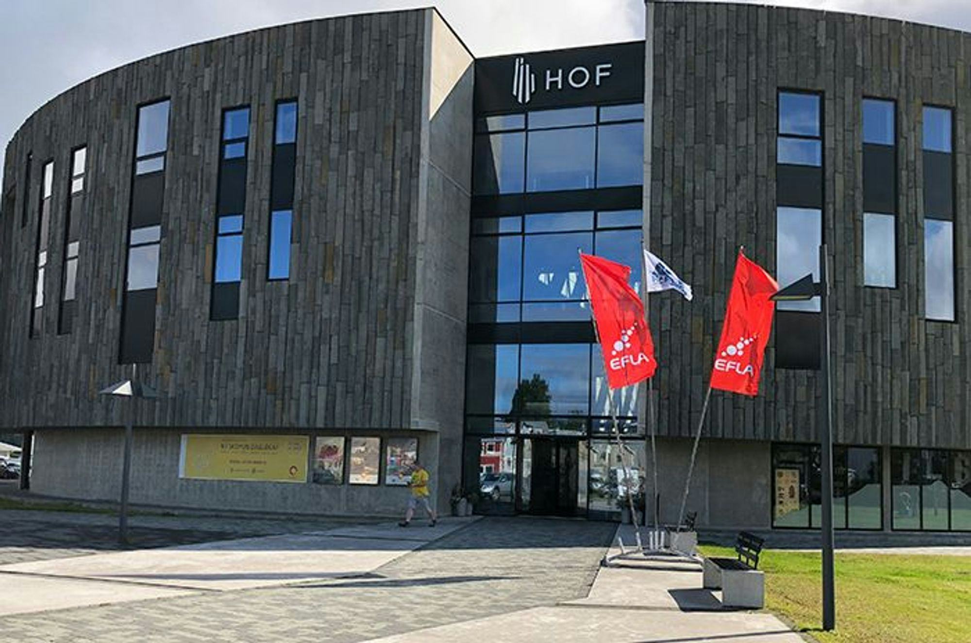 A modern building with two red flag in front, under a clear sky