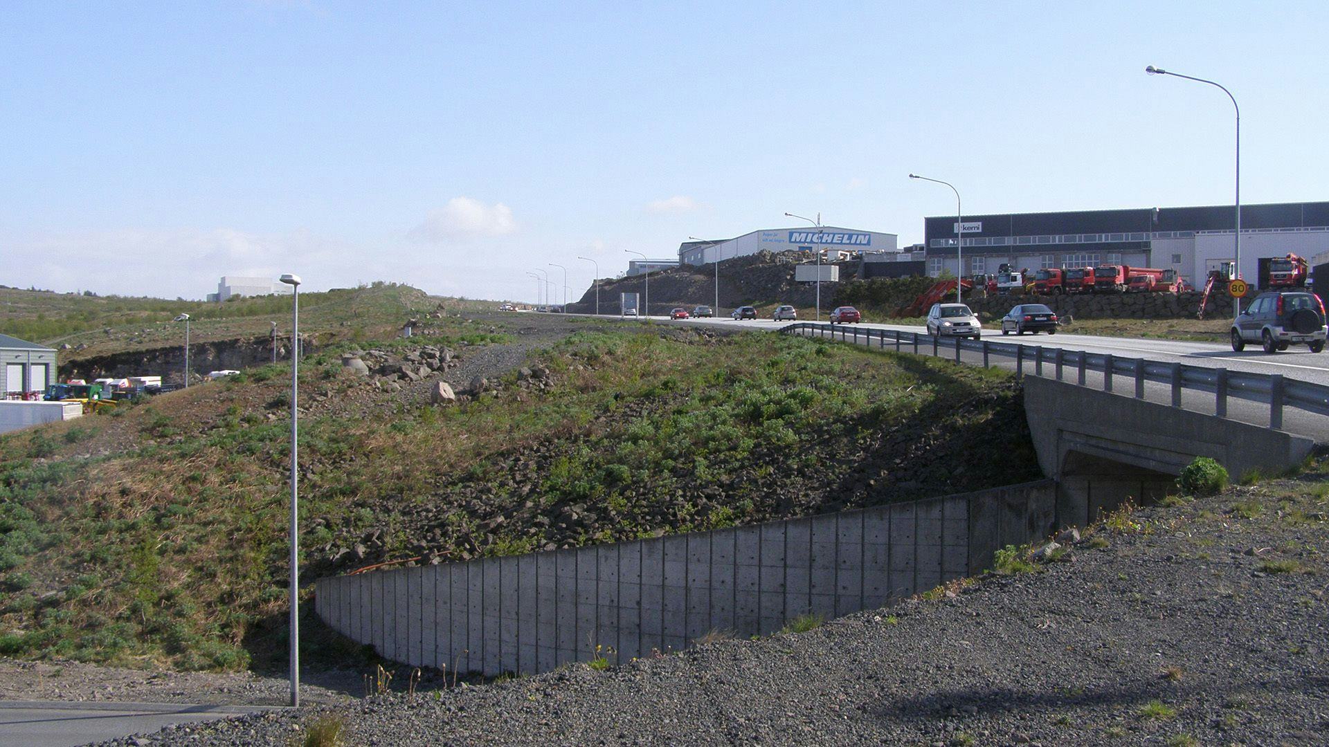 A road with cars and grassy embankment in the foreground 
