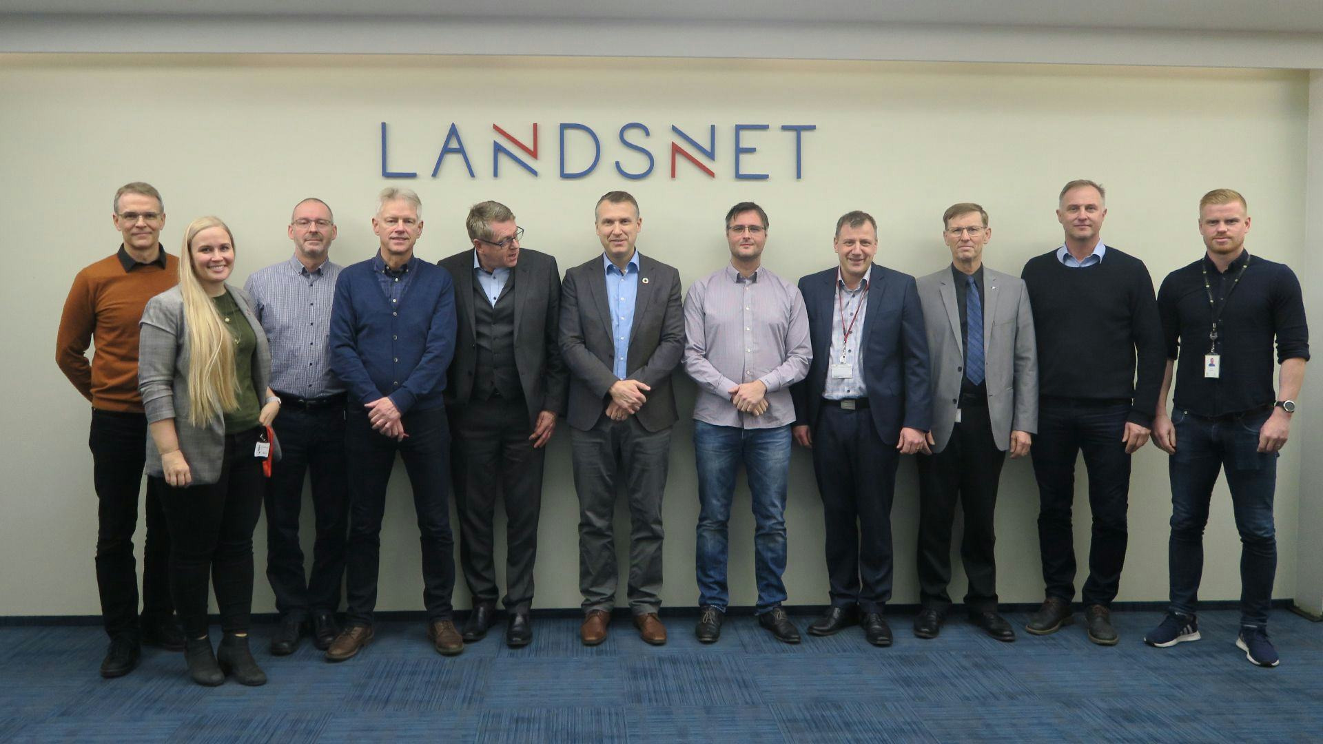 A large group of people standing together against a wall with logo "LANDSNET"
