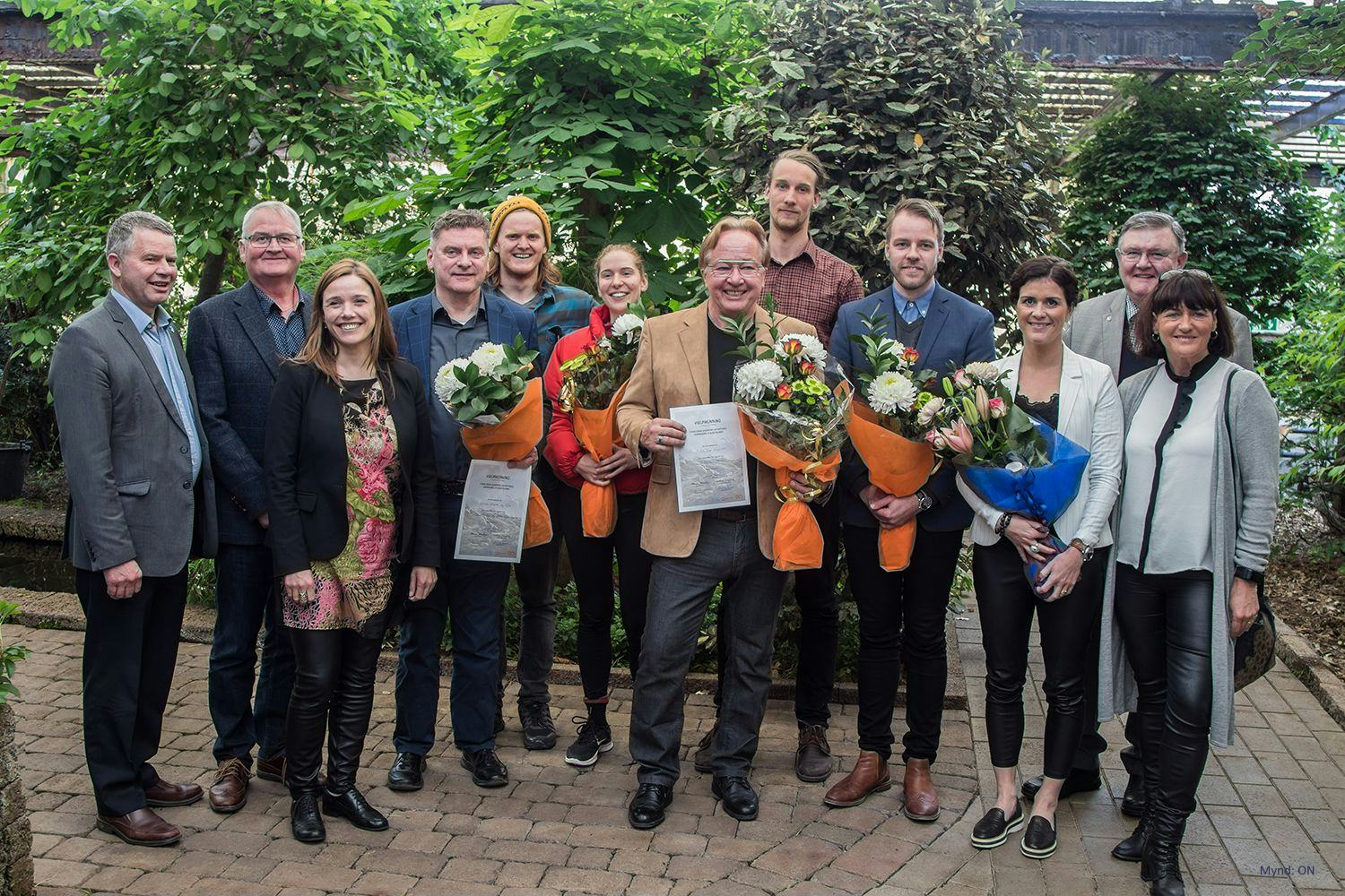 a group of people smiling and holding certificates and bouquets