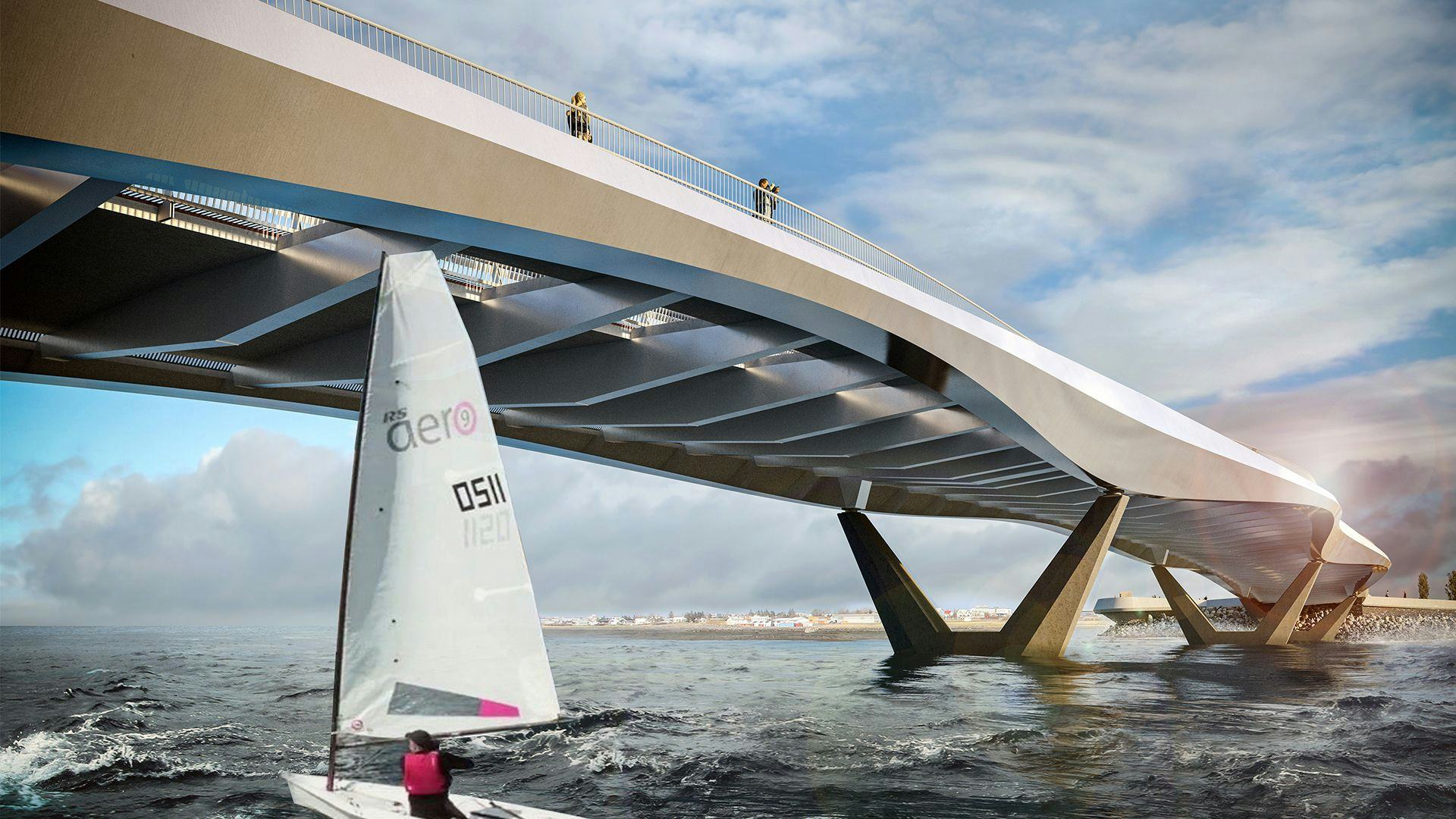 A modern sail boat sailing under a large bridge 