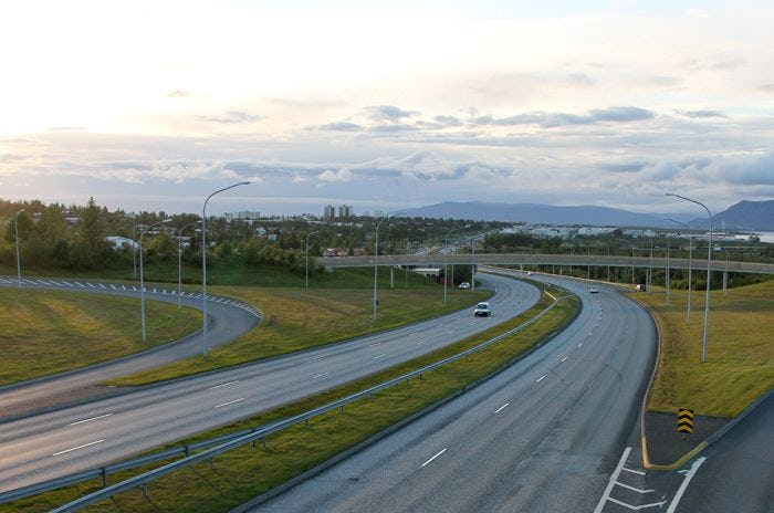 A photo of curving highway with a view of a city skyline